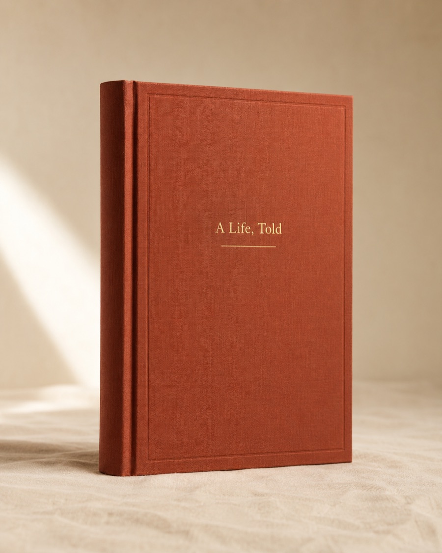 The Told hardcover book — deep terracotta cloth cover with 'A Life, Told' foil-stamped in cream serif type